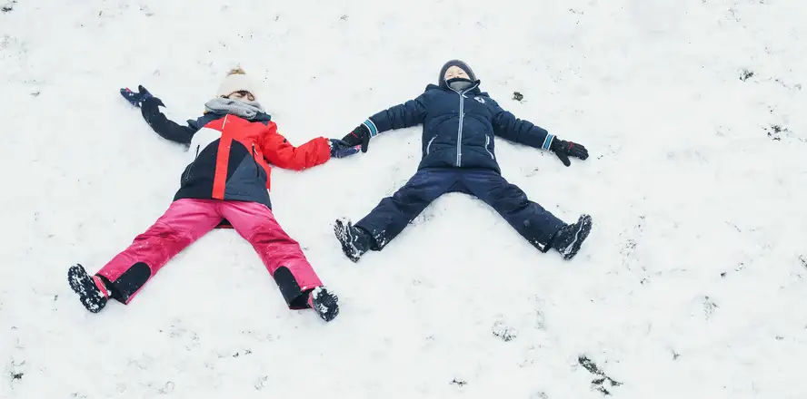 holčička a chlapec leží ve sněhu