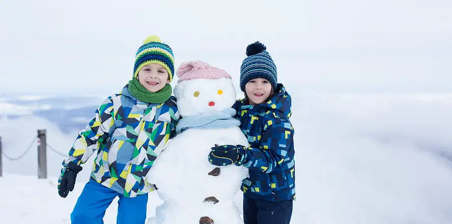 Děti stavící sněhuláka v zimě