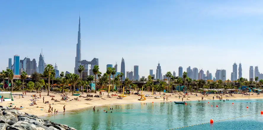 Písečná pláž v Dubaji s mrakodrapy v dálce