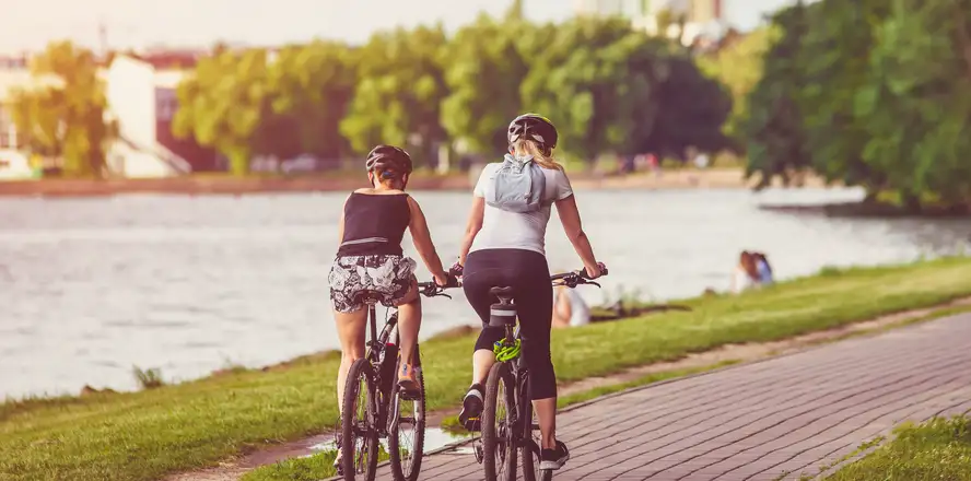 Ženy jedoucí na kole okolo jezera